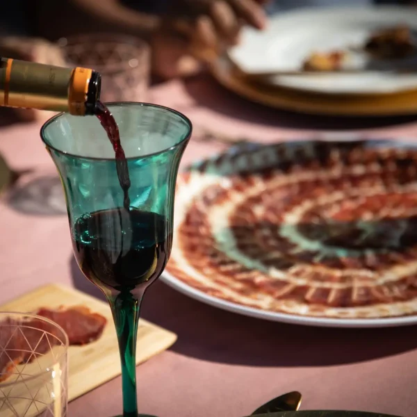 Red wine being poured next to a plate of Iberico ham
